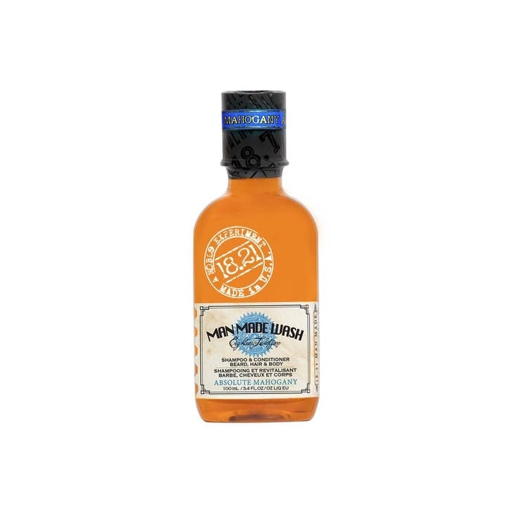Travel-size bottle of Man Made Wash in a clear container with blue liquid.