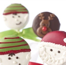 Chocolate-covered Oreo cookie on a stick decorated with red Santa hat.