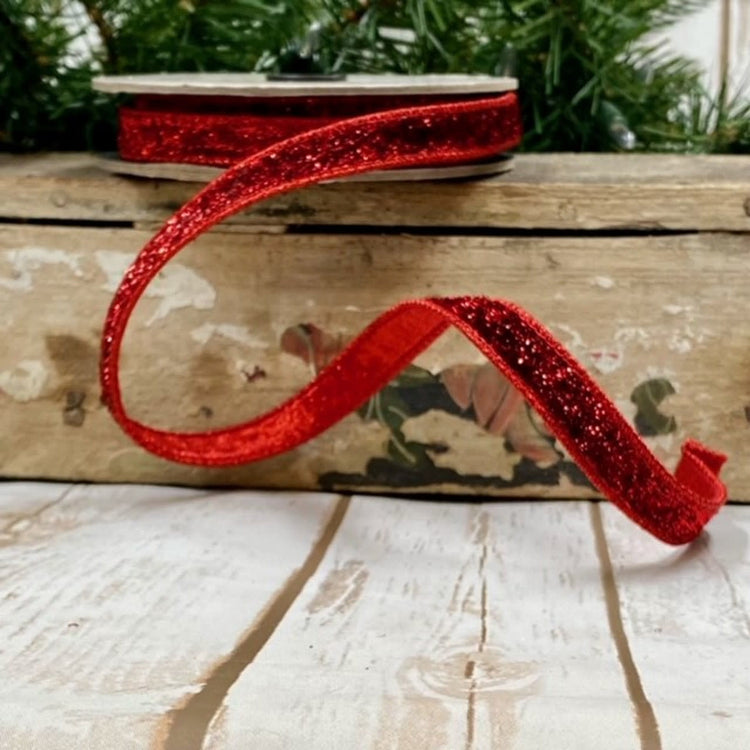 A spool of 0.5-inch wide red metallic velvet ribbon with a lame backing.