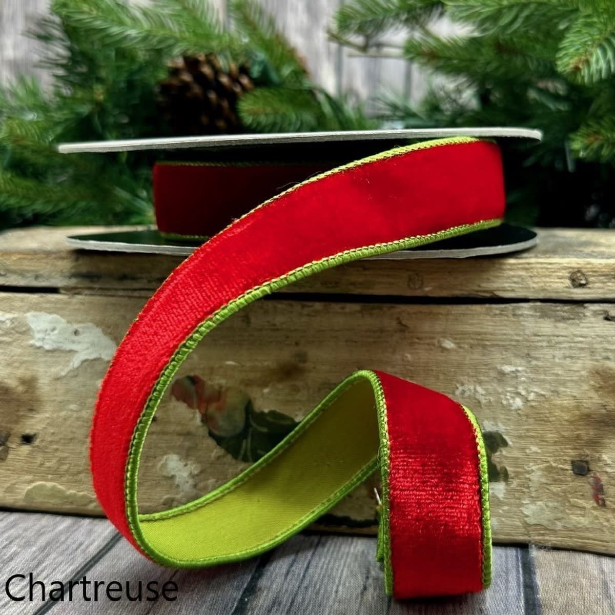 One-inch wide red velvet ribbon with chartreuse green stitched edges on a spool.