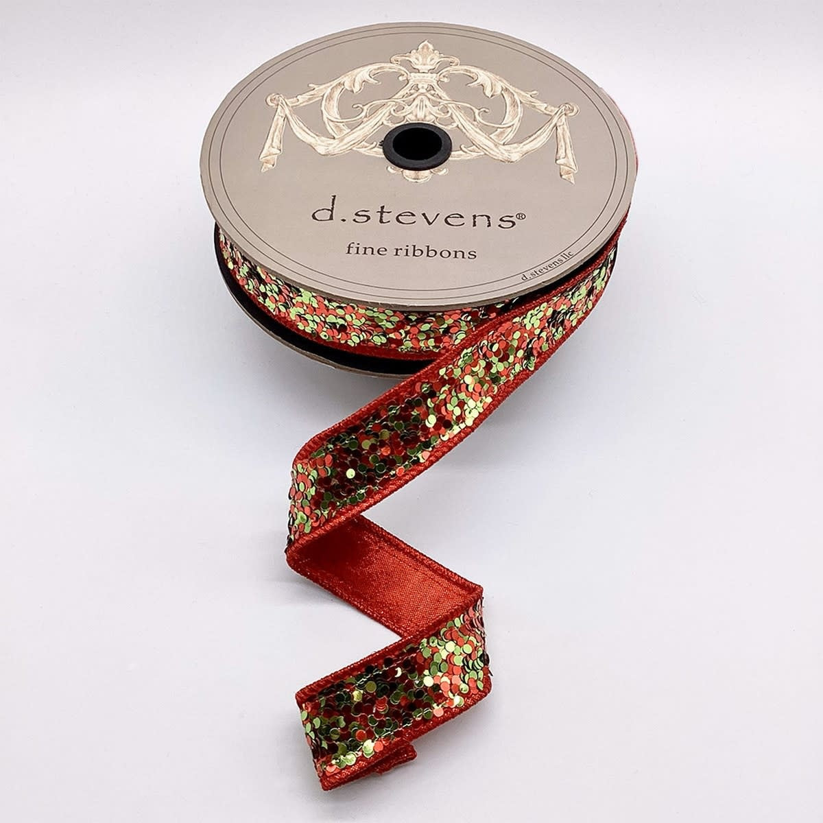 A spool of 1-inch wide red ribbon covered in lime green and red circular glitter sequins.