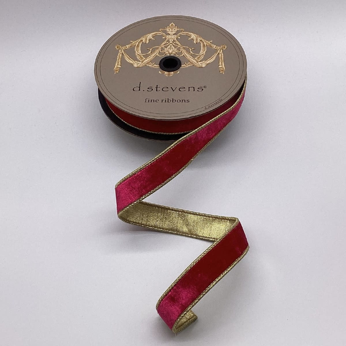 Spool of hot pink velvet ribbon with a metallic gold backing and gold-trimmed edges.