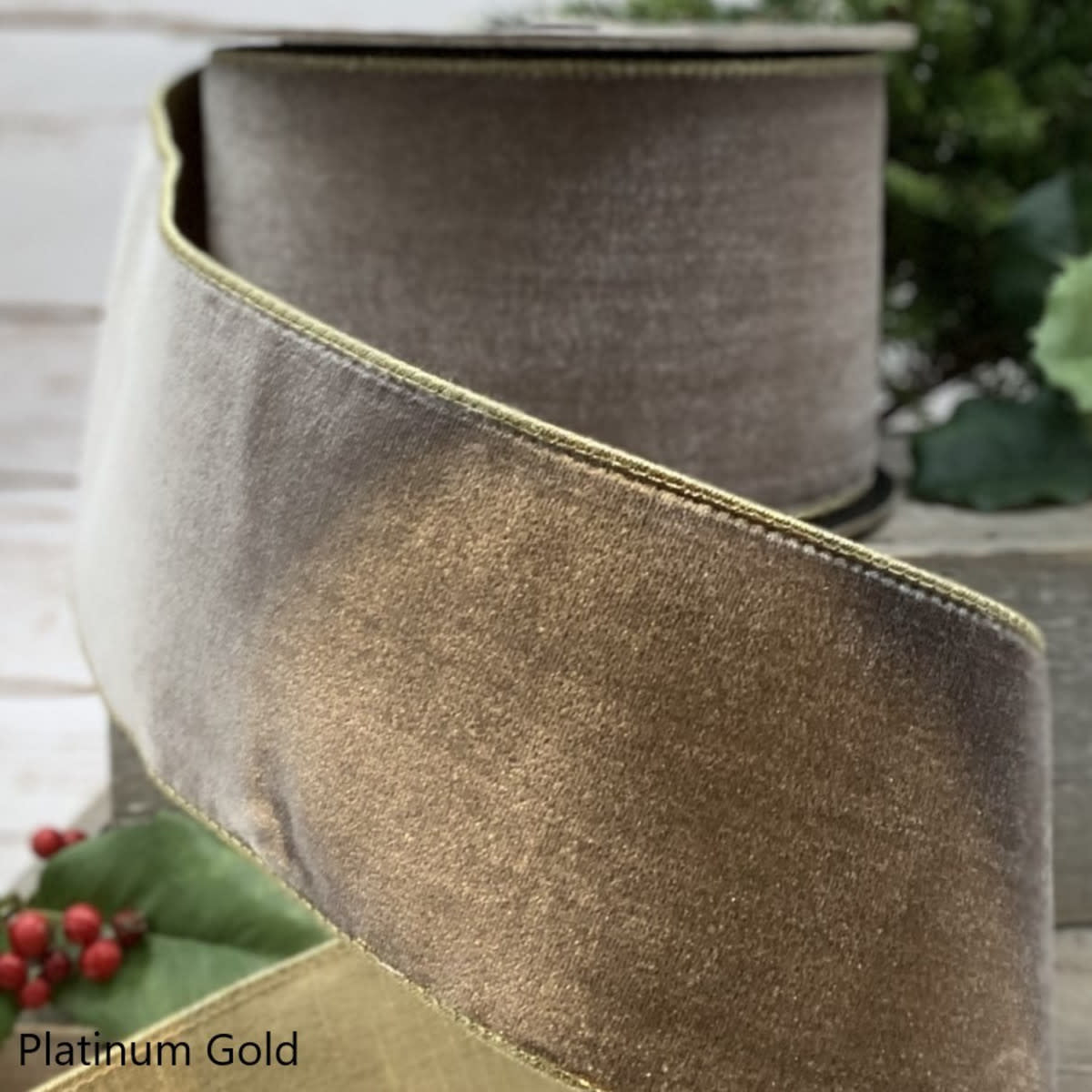 A roll of platinum gold velvet ribbon with a metallic finish and gold stitched edges.