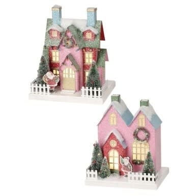 Two pink cardboard Christmas village houses with LED lights, snow accents, and white picket fences.