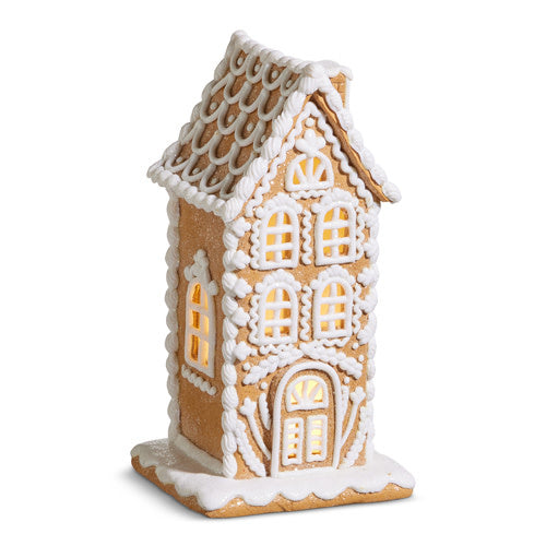 10-inch tall clay dough gingerbread house with white icing details and warm interior lighting.