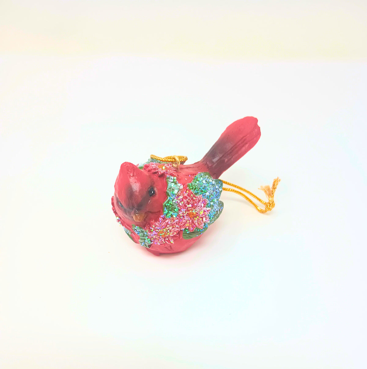 Red cardinal ornament with green wreath detail on a gold hook