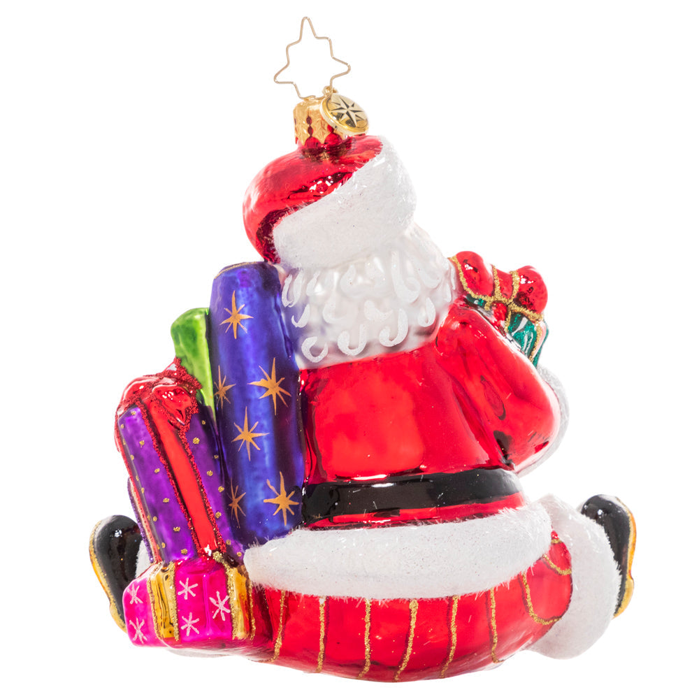 Santa figurine holding wrapped gifts in red suit with white beard