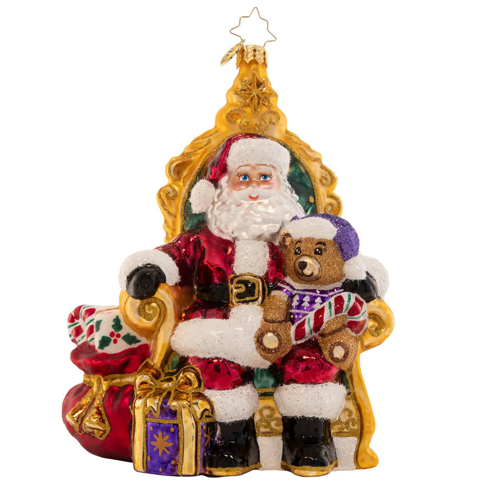 Strike A Pose Santa figurine in red suit seated on a chair surrounded by gifts.