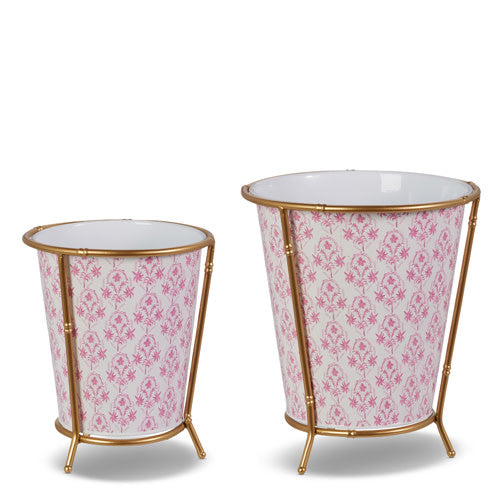 Two pink and white floral patterned cache pots with gold iron stands of different heights.