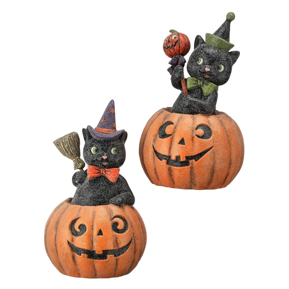 Two black cat figurines in pumpkin bases with witch hats, holding a broom and a small pumpkin.