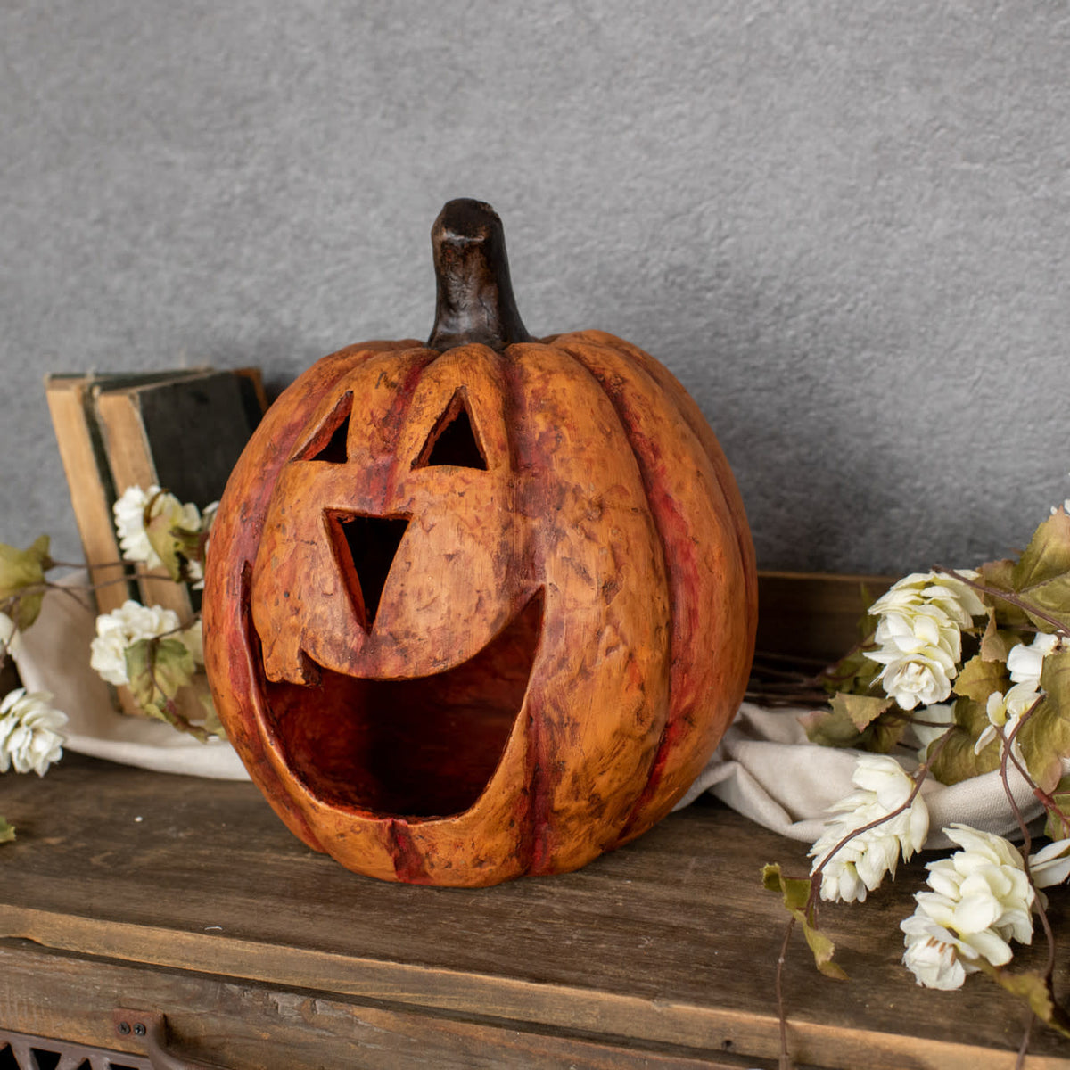 11-inch orange mache pumpkin luminary with a carved big mouth face on a wooden surface.