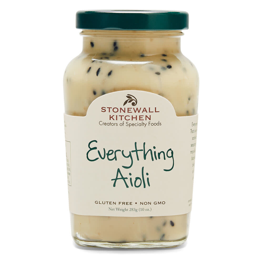 A jar of creamy Everything Aioli topped with black sesame seeds, dried garlic, and sea salt.