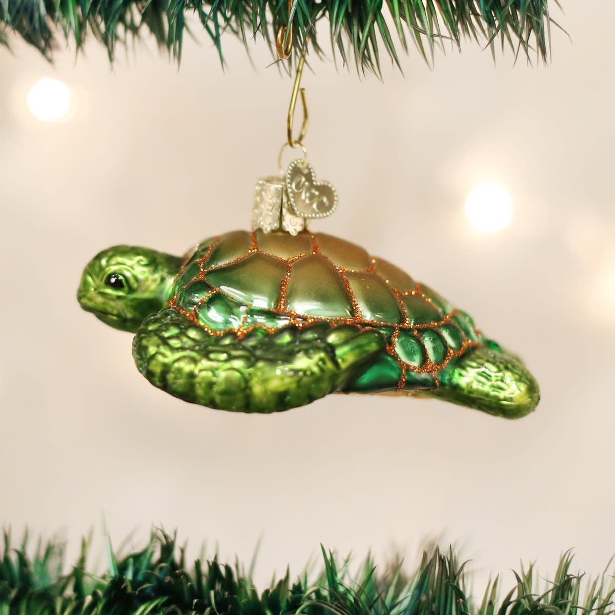 Green sea turtle ornament with detailed shell texture on a natural wood stand.