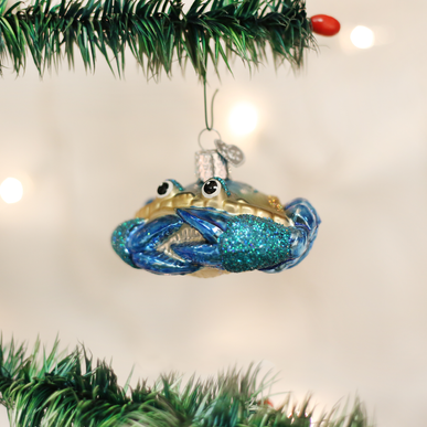 Blue crab zodiac ornament with detailed claws on a natural wood base.