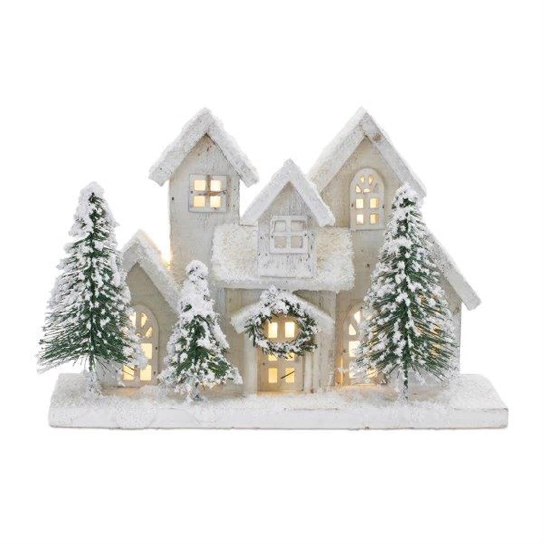 Snow-covered wooden house decoration with LED lights, a wreath, and miniature pine trees.