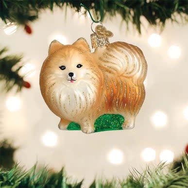 Standing Pomeranian ornament in cream faux fur with black eyes on a gold stand.