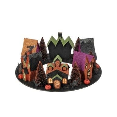 Round cardboard Halloween village display with glittery houses, trees, and pumpkins on a black base.