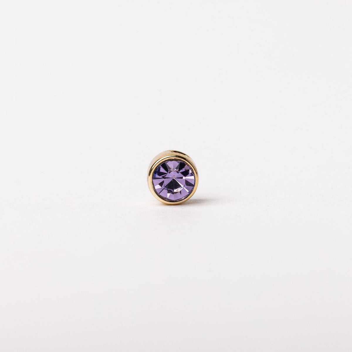 Round gold-tone stud earring featuring a faceted purple crystal center.
