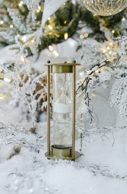 Antique brass sand timer with patina finish featuring a classic hourglass silhouette.
