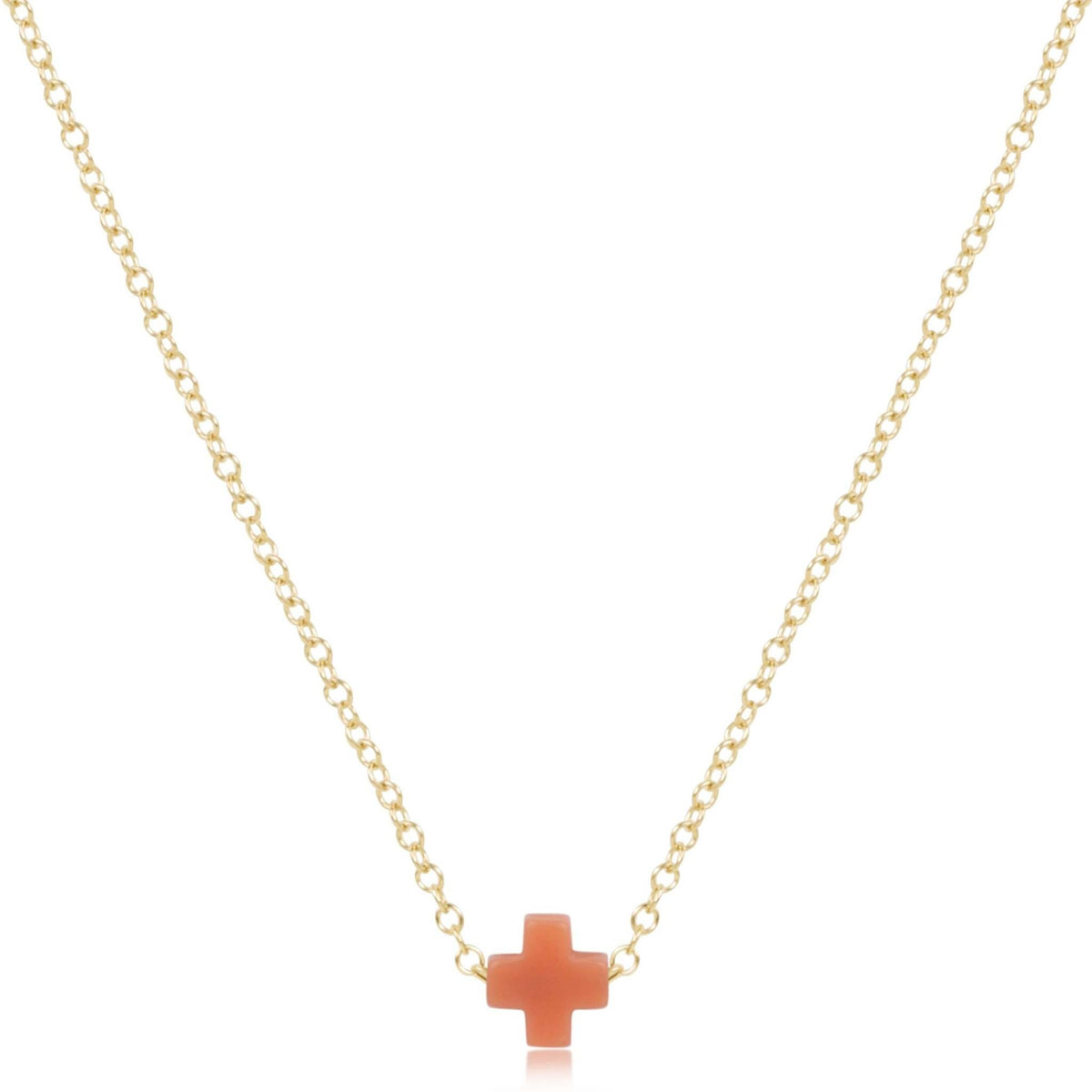 Gold-filled 16-inch necklace featuring a small signature cross pendant on a coral background.