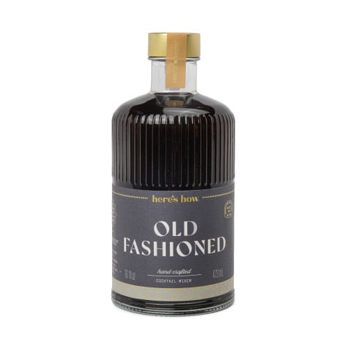 Clear fluted glass bottle with gold foil label holding cocktail mixer