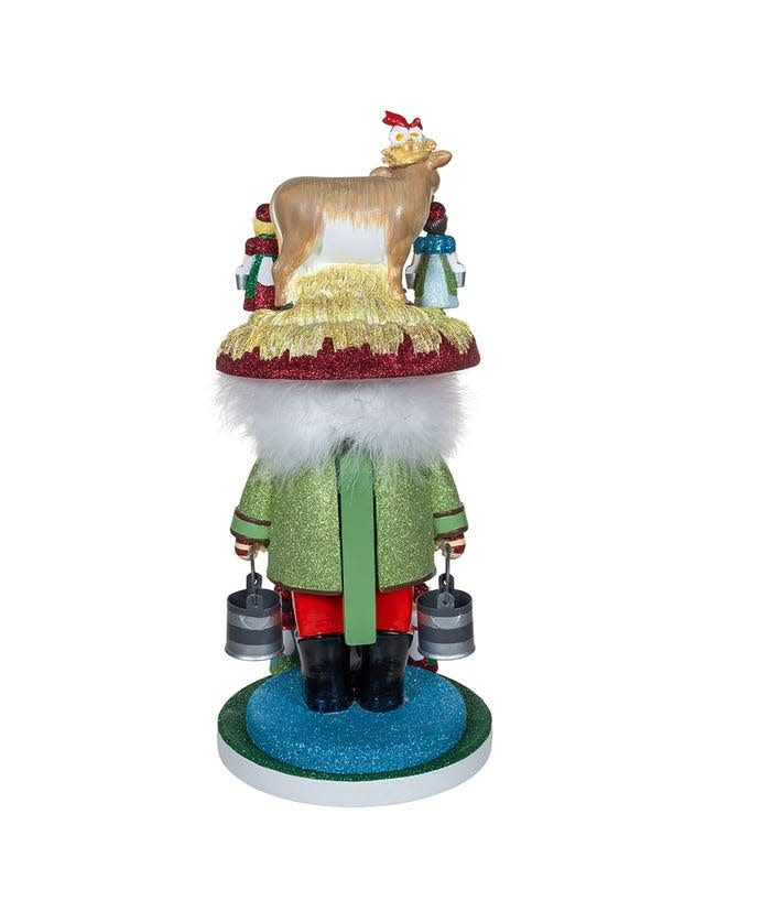 Wooden nutcracker figurine featuring eight maids in a milking pose with red and gold accents.