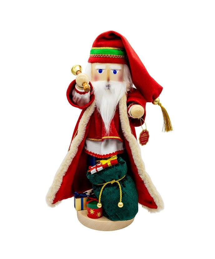 Wooden nutcracker figurine of Santa in red with fur trim holding a staff against white background