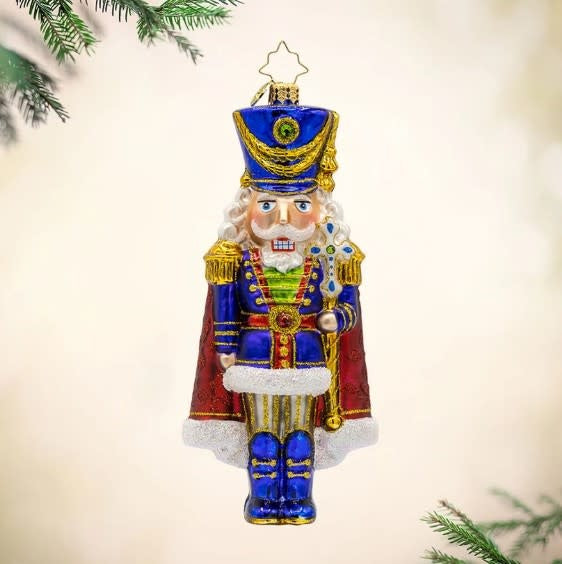 Long Coat Nutcracker figurine in navy blue with gold trim standing upright.