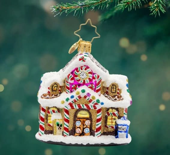 Sweet Tooth Station Gem: a small whimsical train station candy dispenser in pastel pink and white with blue roof accents.