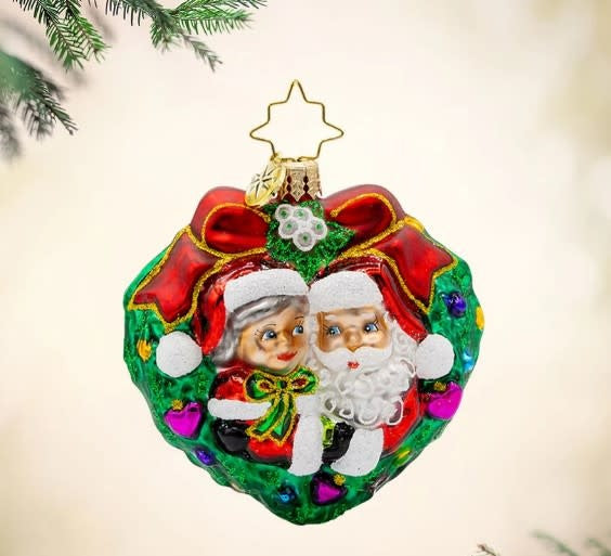 Mr. & Mrs. Claus mistletoe ornament set with green foliage accents and red figures.