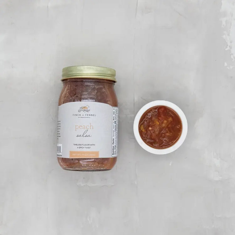 Open jar of peach salsa with visible chunks of fruit and onions