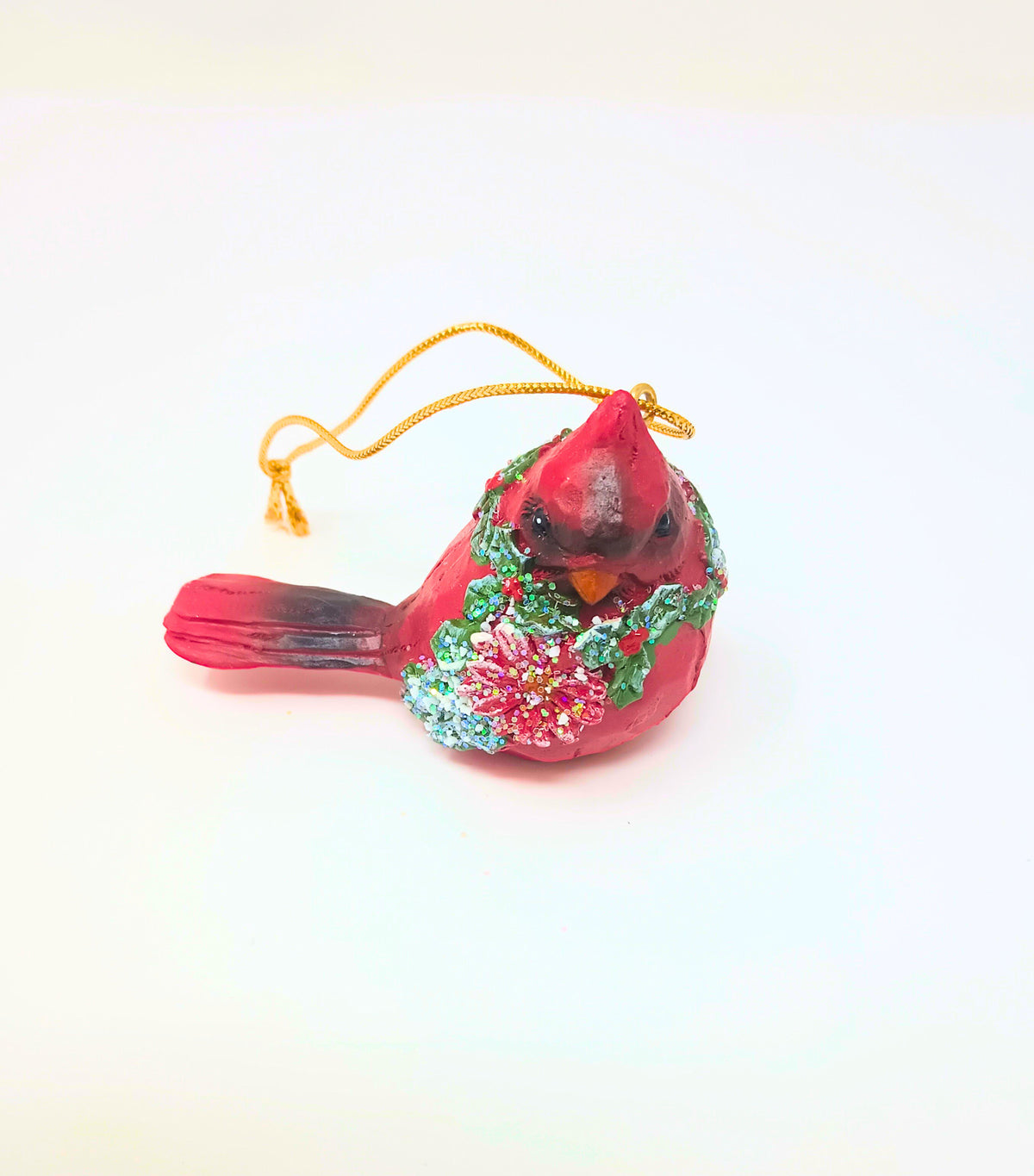 Red cardinal ornament with green wreath detail on a gold hook