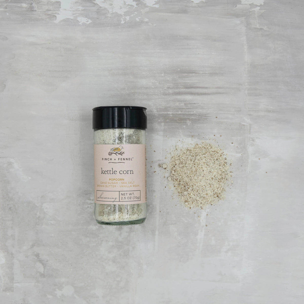 Finch + Fennel Kettle Corn Popcorn Seasoning in a 2.5 oz glass jar next to a pile of seasoning.