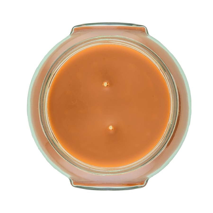 A large cylindrical cowboy-themed candle with a dark wax body, metallic accents, and visible wicks.