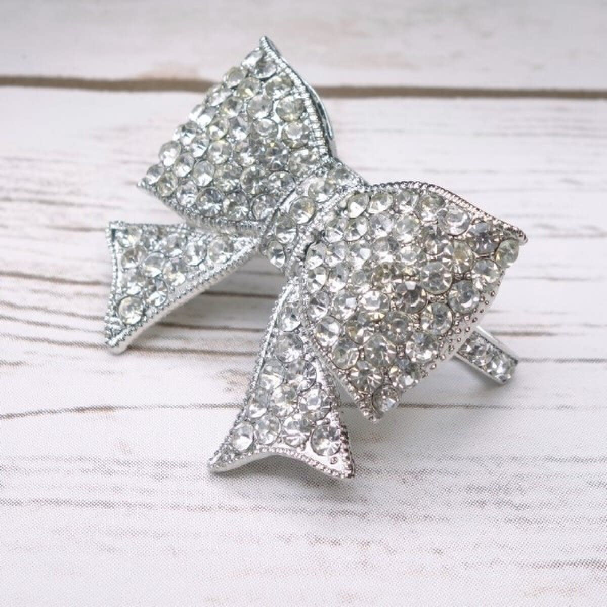 Silver napkin ring featuring a bow silhouette encrusted with clear sparkling crystals.