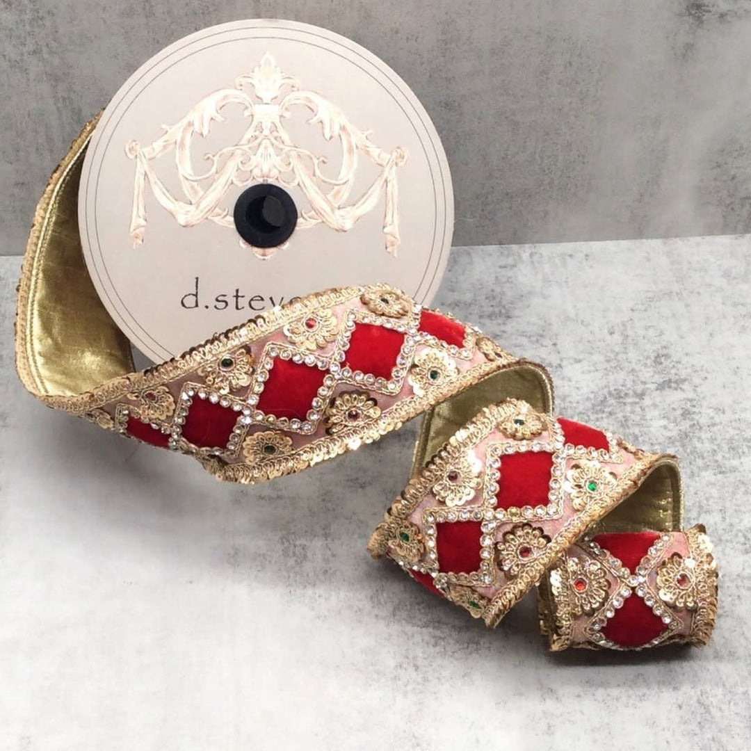 Red velvet ribbon with gold floral diamond patterns and jewel sequins on a spool.
