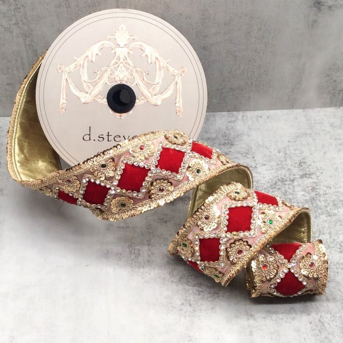 Red velvet ribbon with gold floral diamond patterns and jewel sequins on a spool.