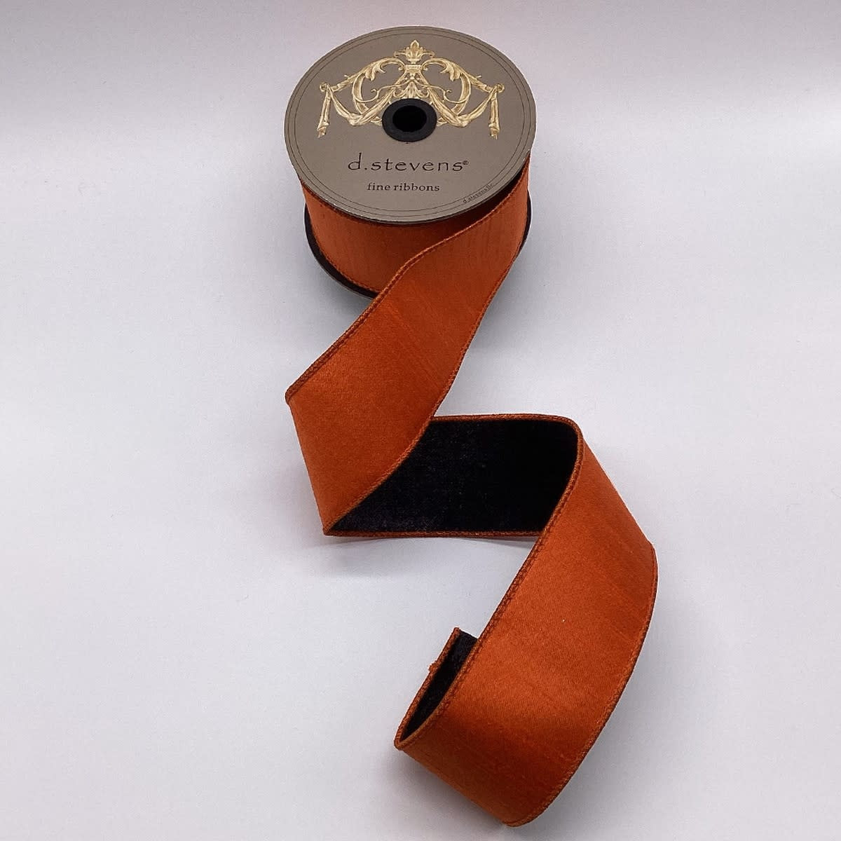 2.5-inch by 10-yard orange and black double-sided metallic dupion ribbon on a spool.