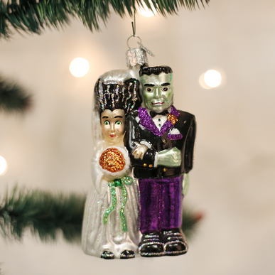 Frankenstein & Bride Halloween ornament featuring a green monster figure with bolts holding hands with a pale bride in black dress.