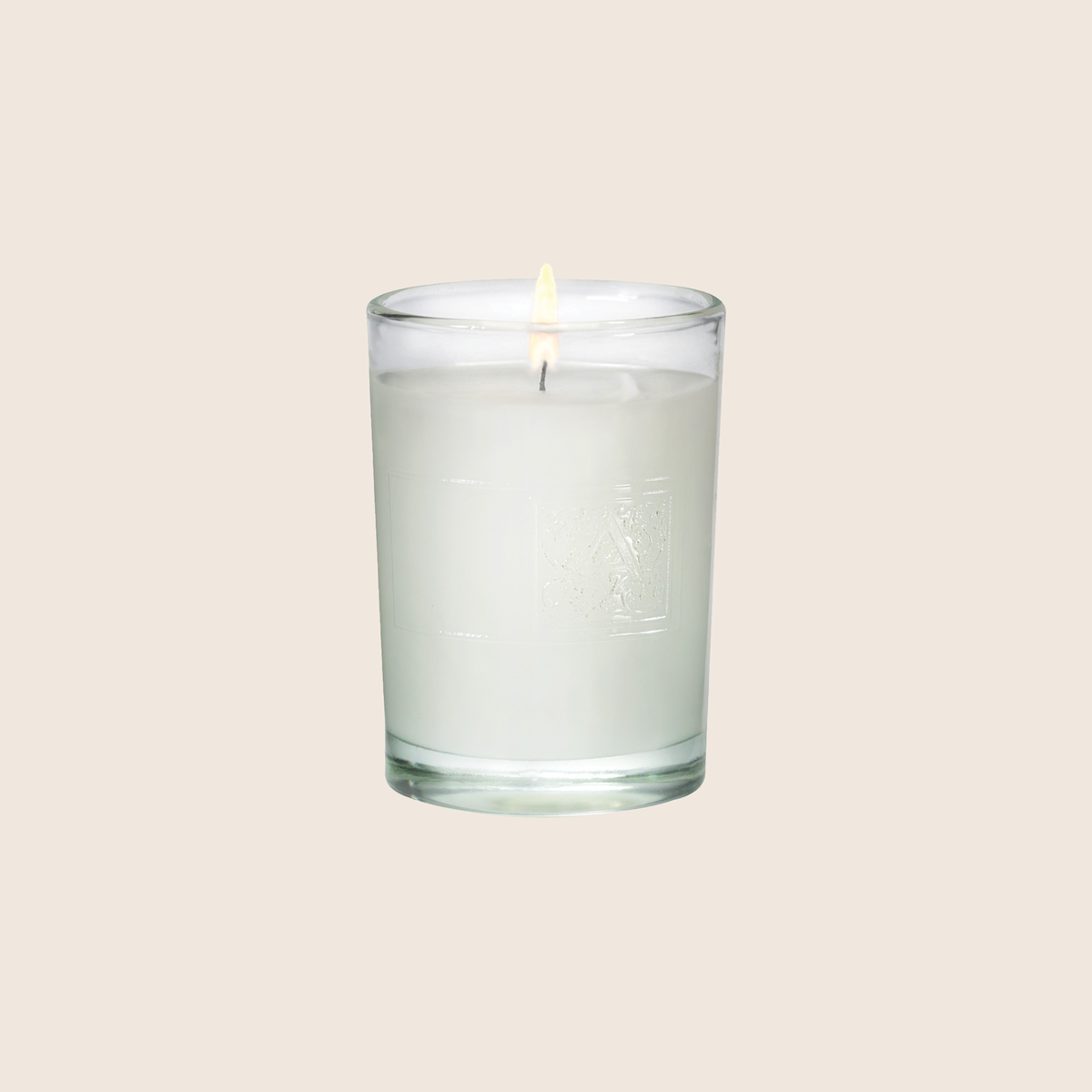 2.7 oz Juniper Berry votive candle in a clear glass cylinder with white wax and a lit wick.