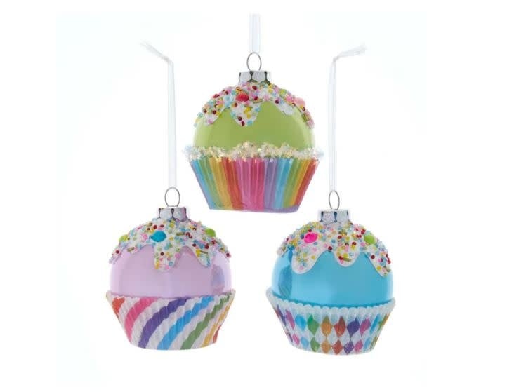 Three glass cupcake ornaments in pink, green, and blue with white icing and colorful sprinkles.