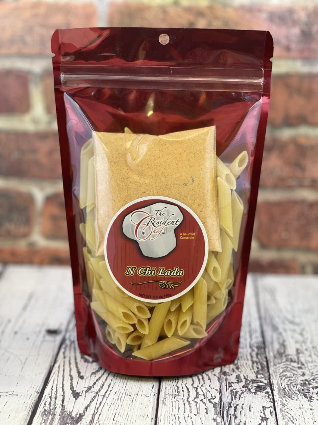 Open jar of N Chi Lada Casserole with a red lid showing the food product inside.