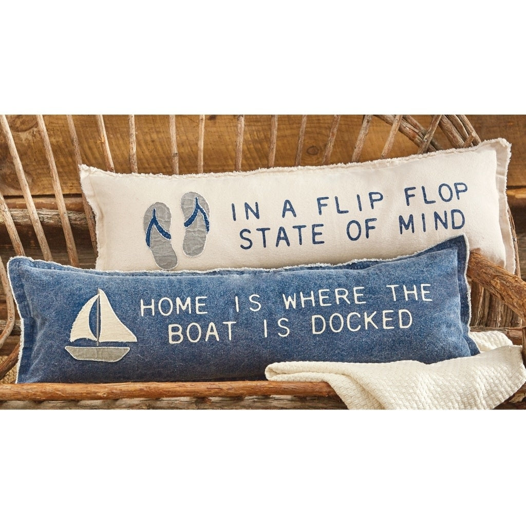 Washed canvas long pillow with printed sentiment, applique icon trim, fringe edge, and zipper closure.