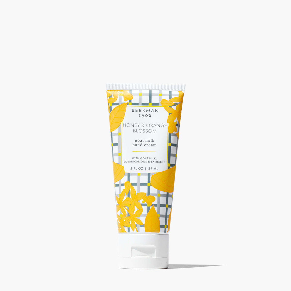 Beekman 1802 Honey & Orange Blossom goat milk hand cream in a 2 oz tube with yellow floral pattern.