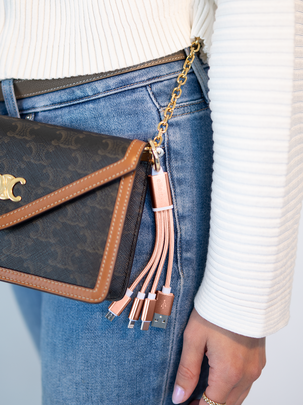 Rose gold 3-in-1 charging cable keychain with braided nylon, attached to a brown handbag.
