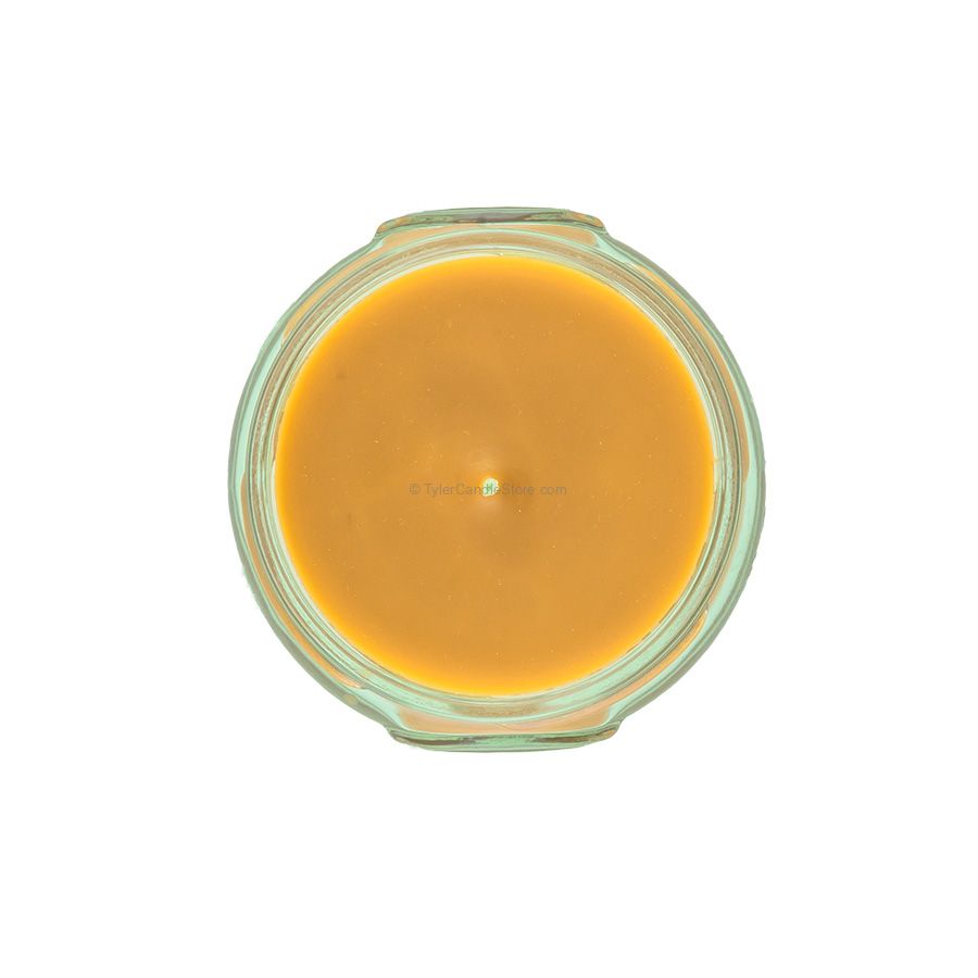 Top view of a 3.4oz Tyler candle in a glass jar with orange wax and a single centered wick.