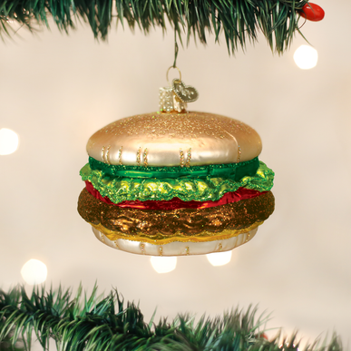 Cheeseburger ornament with sesame seed bun, lettuce, tomato, cheese patty, and beef patty on a white background.