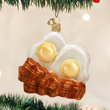 Bacon And Eggs ornament featuring a white egg shape with brown bacon strips wrapped around it.