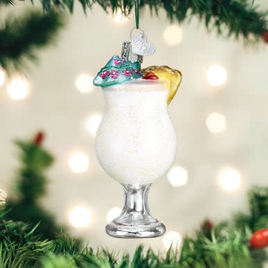 Mouth-blown glass ornament shaped like a hurricane glass filled with yellow pineapple drink and garnished with fruit.