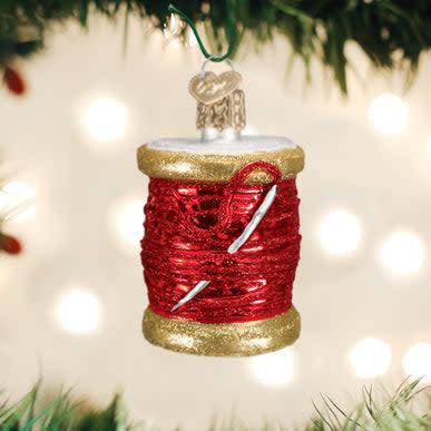 Glass ornament shaped like a red spool of thread with visible winding texture.